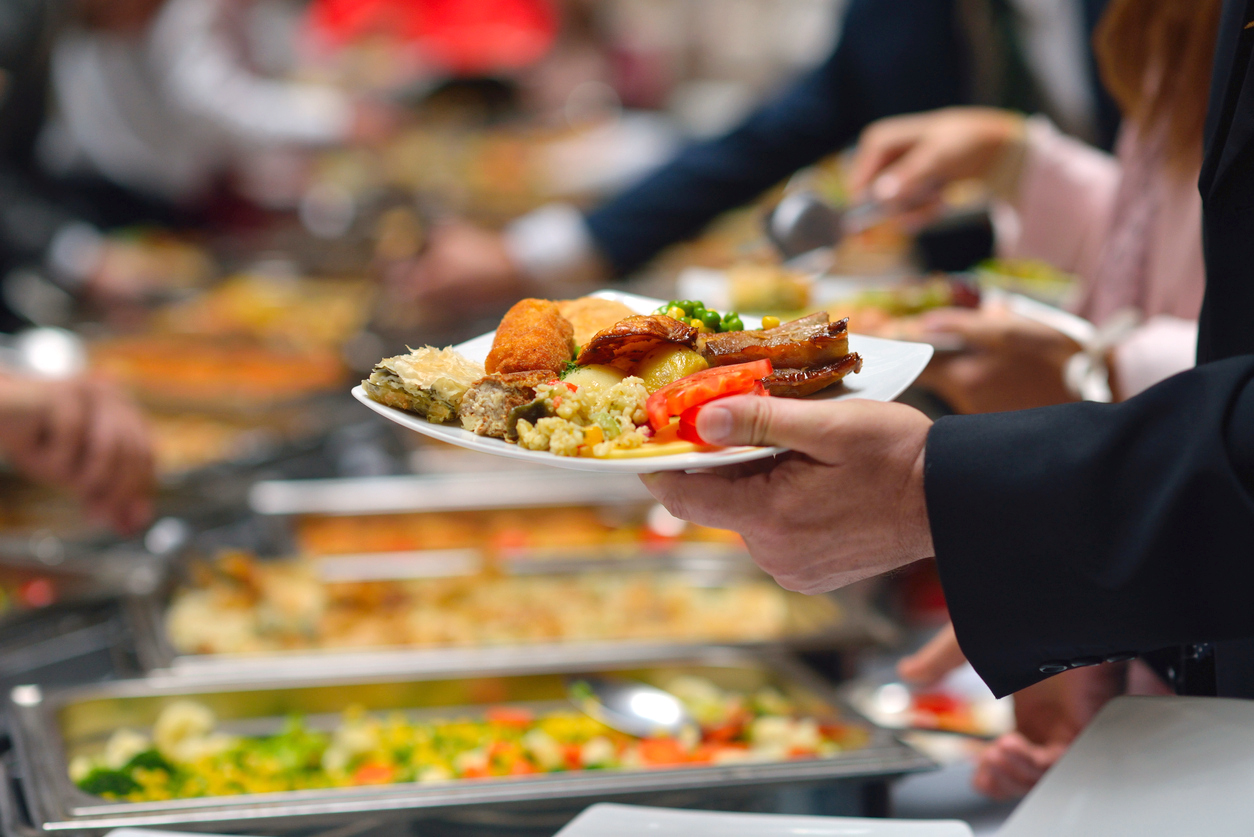 A man holding a plate of food while standing in line at a buffet